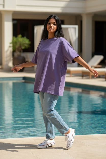 Woman in a purple shirt and light blue jeans standing by a pool.