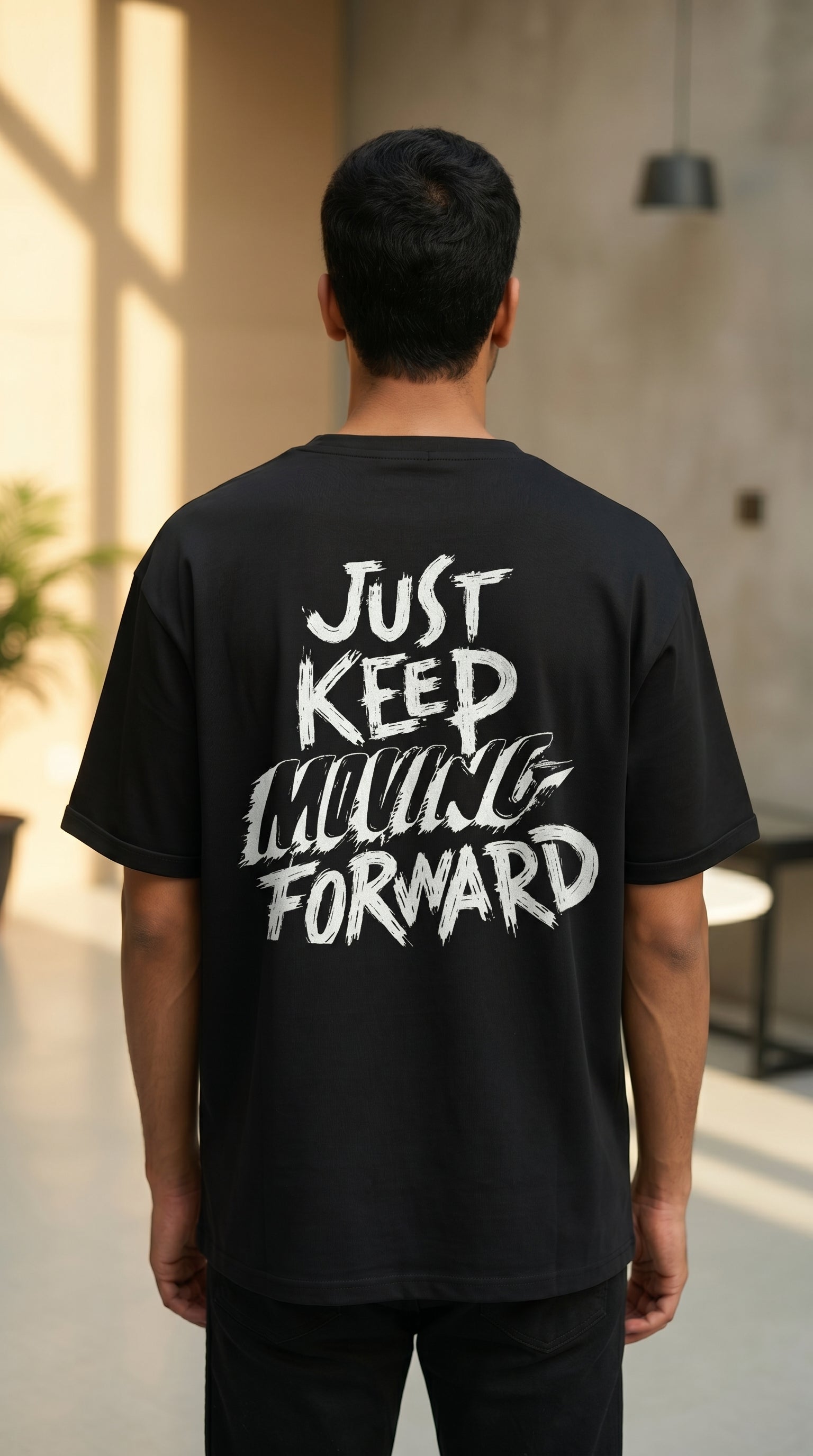 Person wearing a black t-shirt with 'Just Keep Moving Forward' text on the back in an indoor setting.